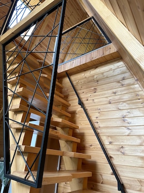 Un escalier en bois avec des rampes en métal, menant à l’étage supérieur.