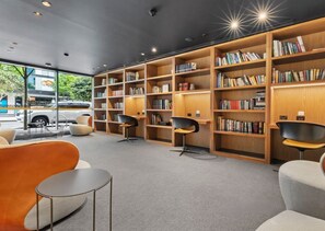 Een moderne bibliotheek met boekenplanken, zitplaatsen en uitzicht op de straat.