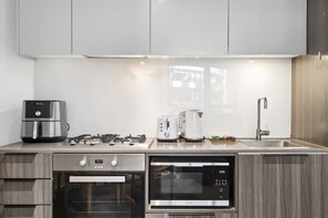 Een moderne keuken met roestvrijstalen apparatuur, waaronder een koffiezetapparaat, broodrooster en oven.