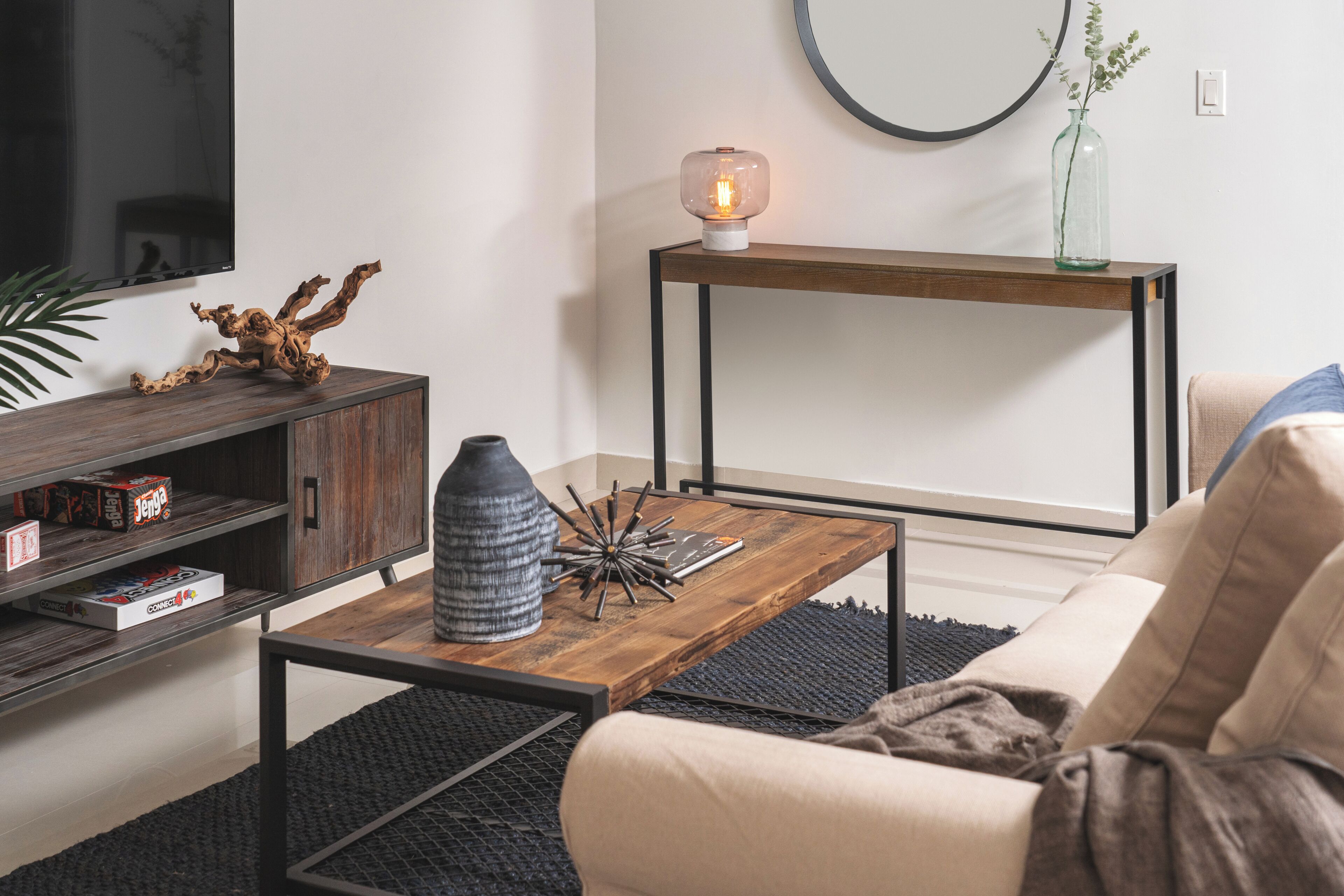 A modern living room with a wooden coffee table, a sofa, a TV, and a console table with a lamp.