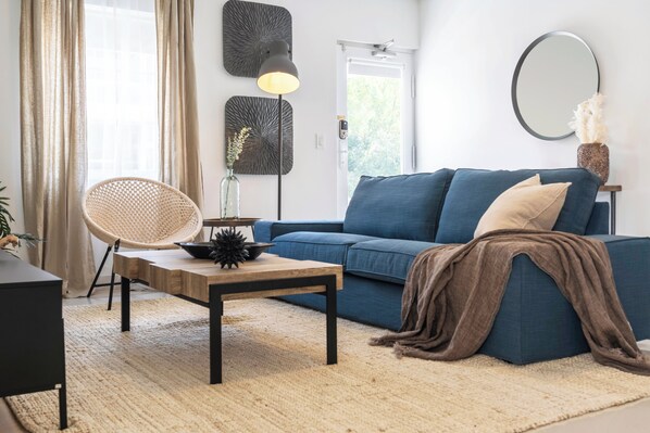 Una sala de estar moderna con un sofá, una mesa de centro, una lámpara y un adorno en la pared.