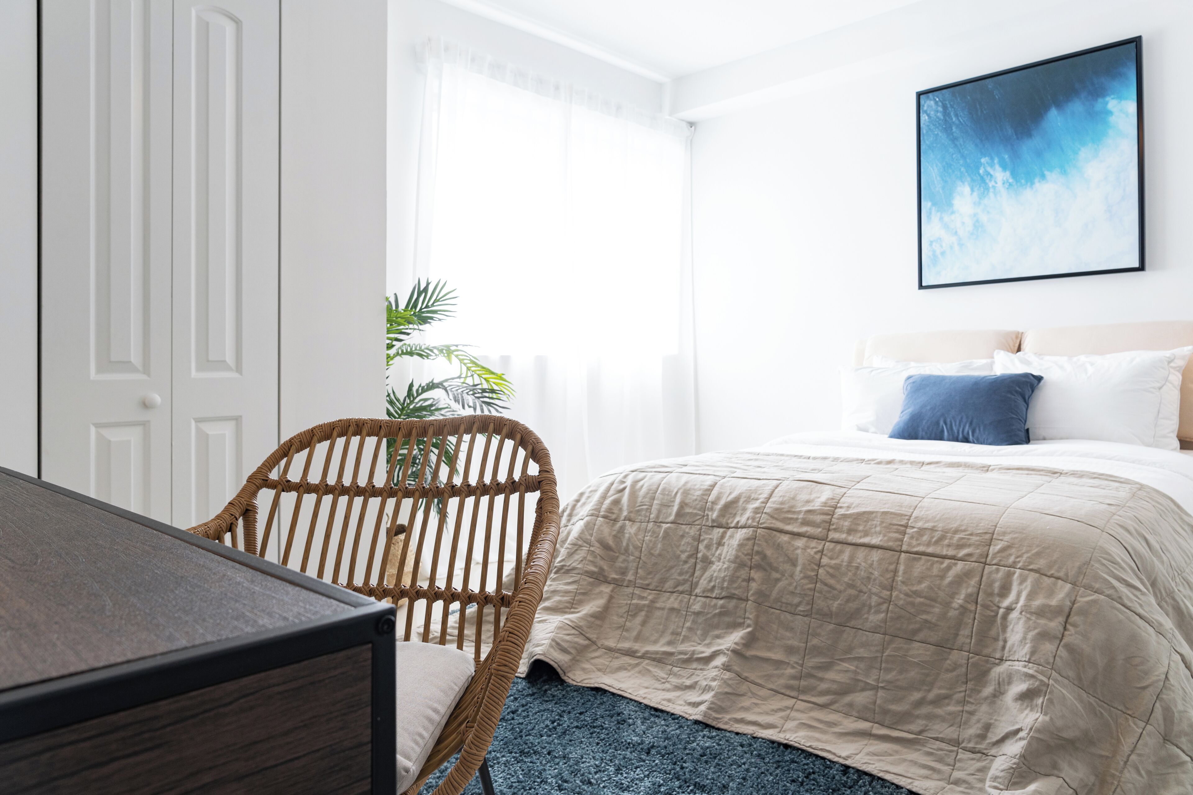 A bedroom with a bed, a chair, a desk, and a window with curtains.