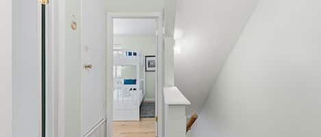 A hallway with a wooden floor leading to a room with bunk beds.