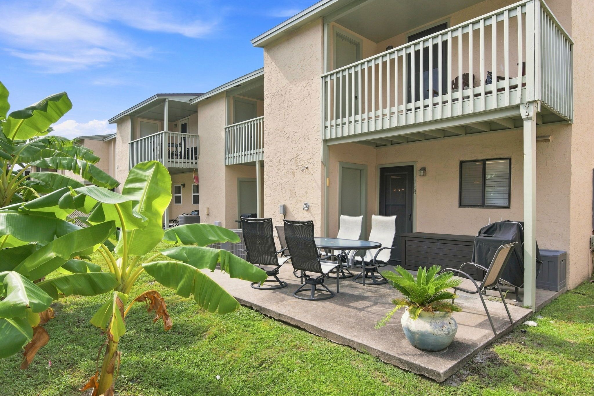 A residential building with a balcony, outdoor seating area, and a potted plant.