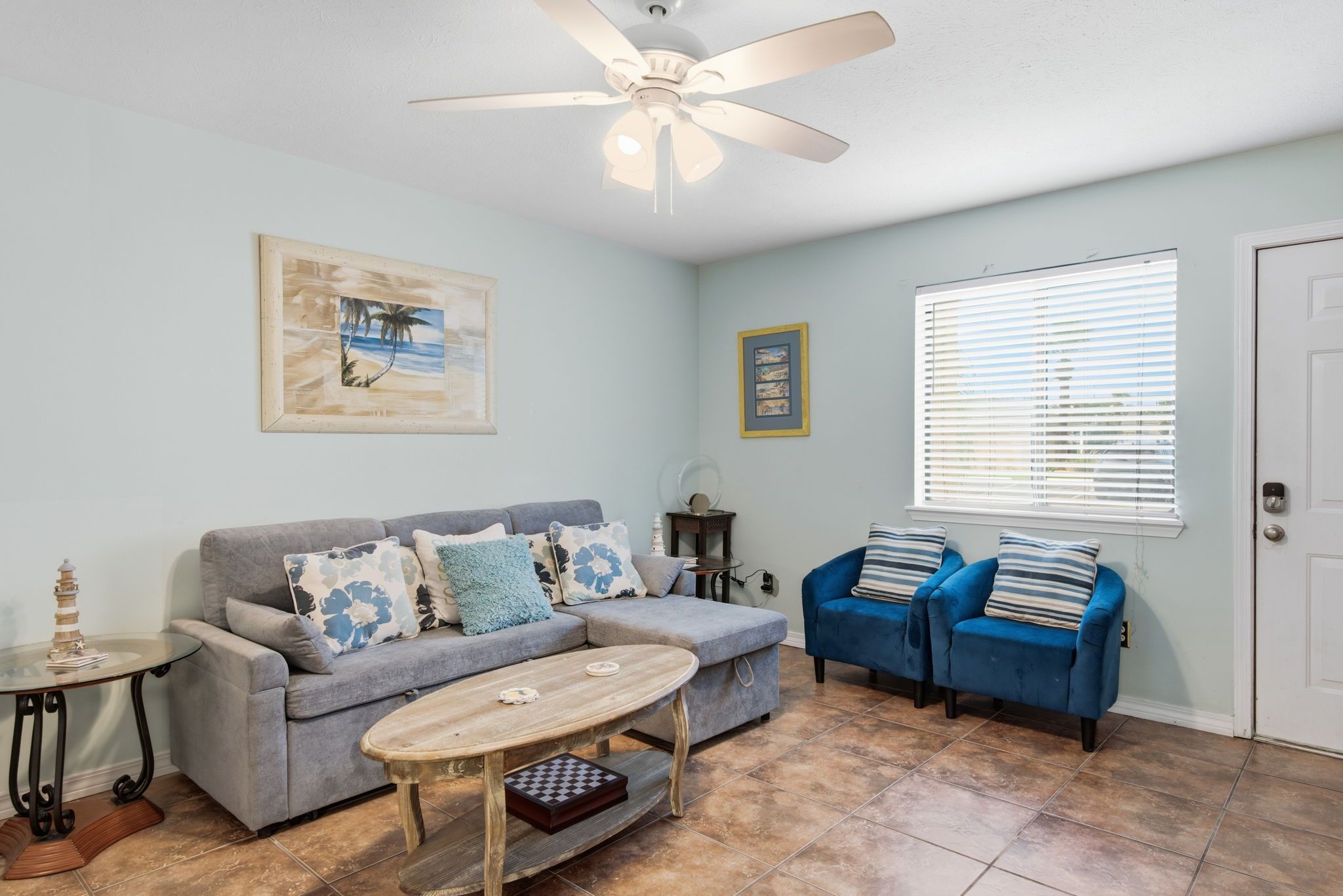 A living room with a gray sofa, a blue sofa, a wooden coffee table, and a ceiling fan.
