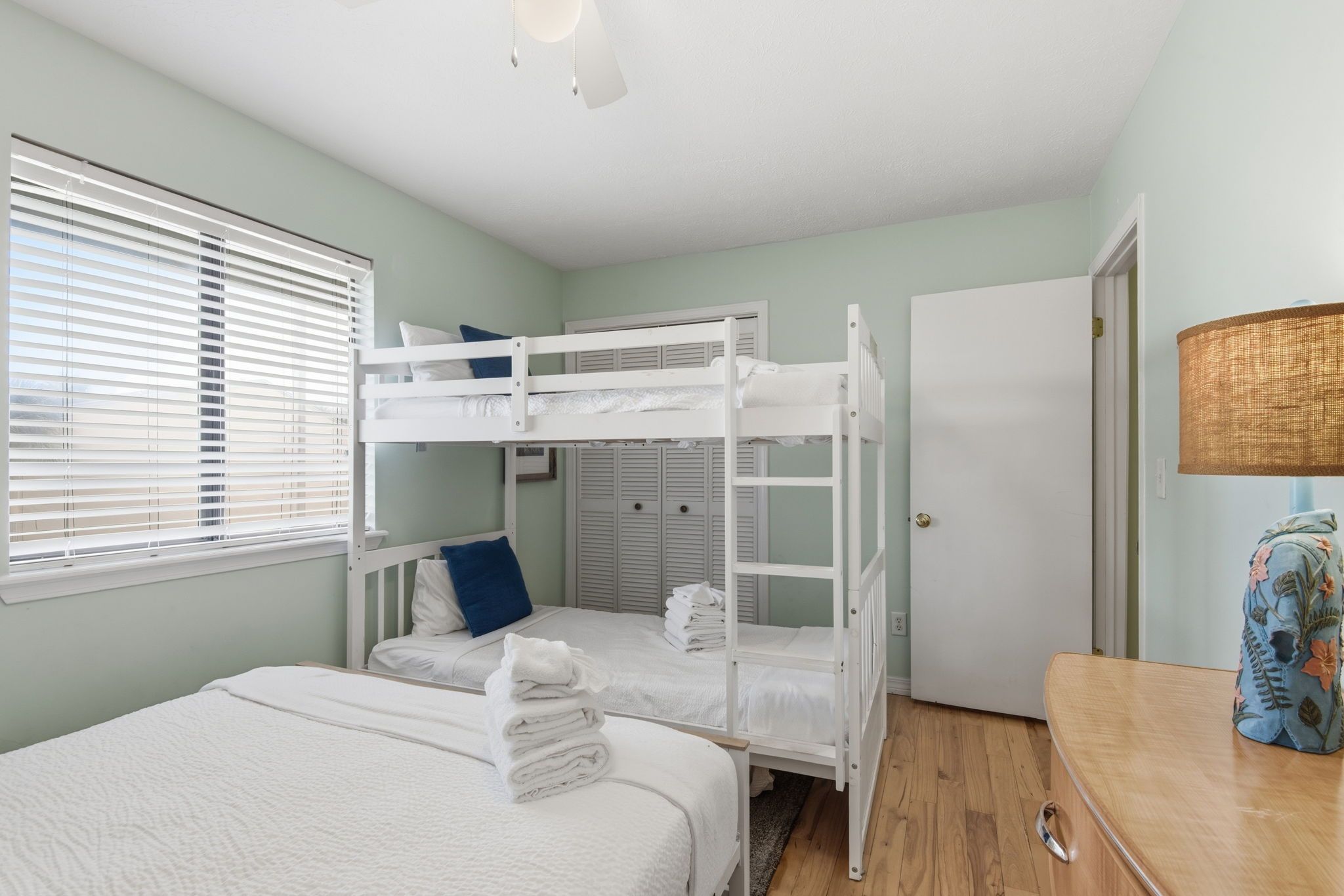 Une chambre avec des lits superposés, une armoire, une porte et une lampe.