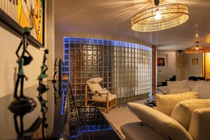 Ein modernes Wohnzimmer mit Glastrennwand, einem Holzstuhl, einer Couch und einer Pendelleuchte.