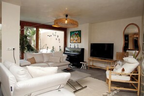 Uma sala de estar moderna com um sofá, uma televisão, um piano e um espelho grande.