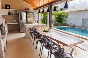 An outdoor kitchen area with a pool, bar, and seating. - Mansion in Maracaipe, 100 meters from the sea, Jacuzzi, Swimming pool, Games room. (Ipojuca)