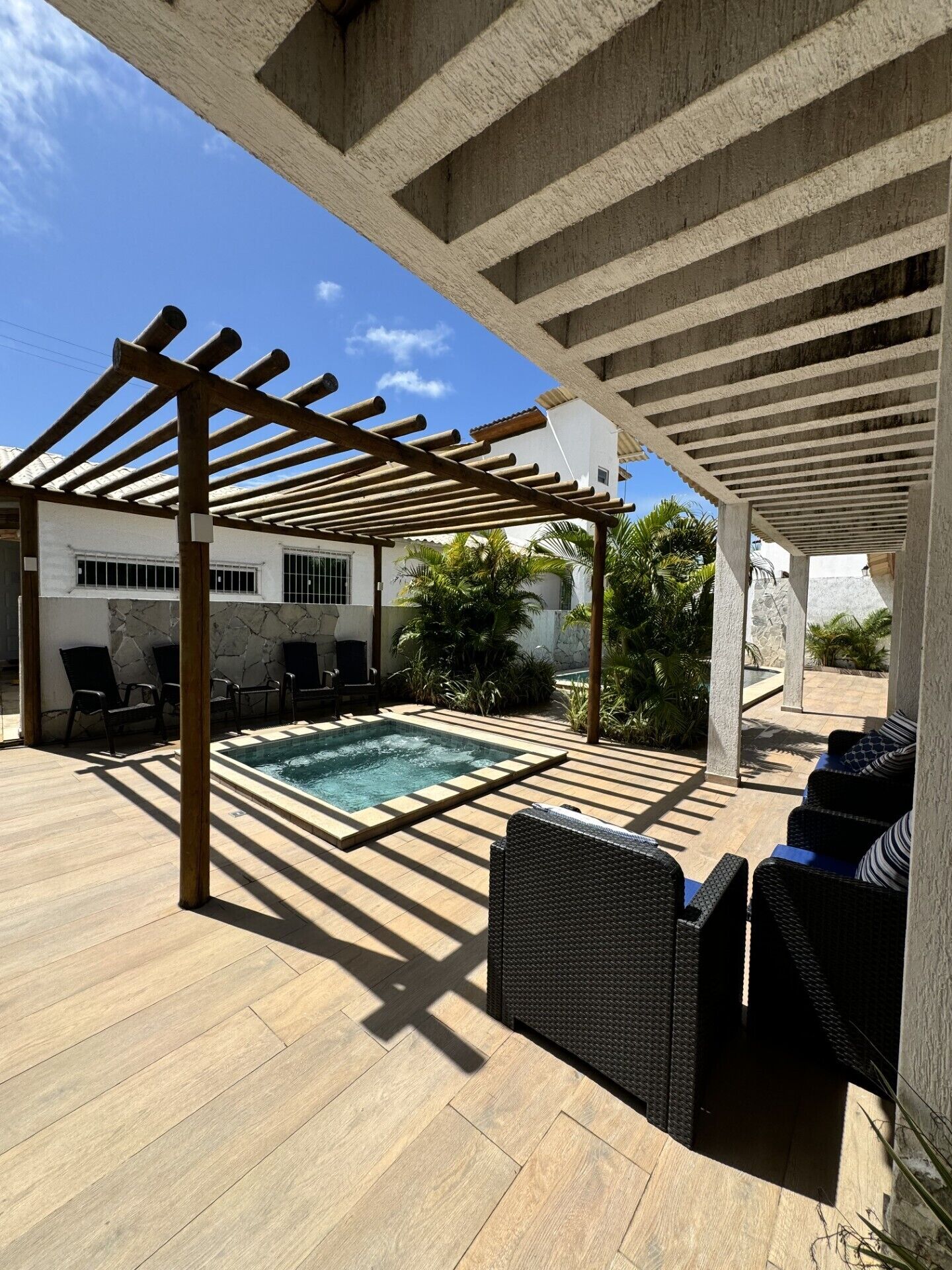 A covered outdoor area with a pool, seating, and a pergola structure.