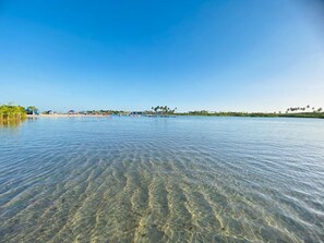 On distingue clairement une étendue d’eau calme, avec une rive lointaine, des bâtiments et de la végétation.