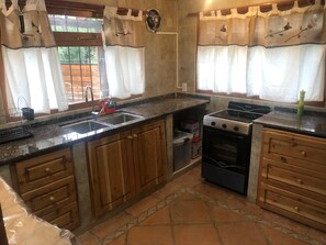 A kitchen with a granite countertop, wooden cabinets, a stove, and a sink. - Wonderful 3-bedroom house in Bariloche, Patagonia awaits you (San Carlos de Bariloche)