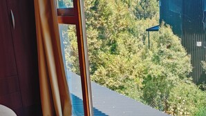 Ein Zimmer mit großem Fenster, Holzboden und einem Bett.