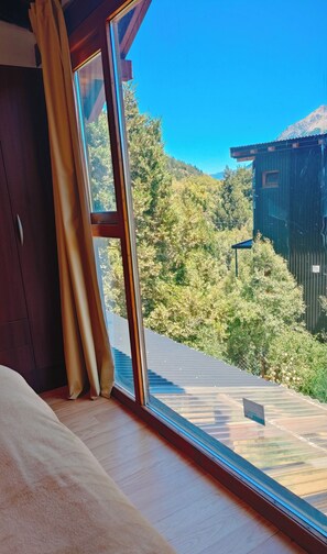 A room with a large window, wooden floor, and a bed. - Wonderful 3-bedroom house in Bariloche, Patagonia awaits you (San Carlos de Bariloche)