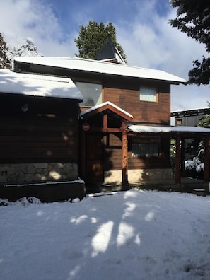 Eine Holzhütte mit einem schneebedeckten Dach und einem Steinfundament.