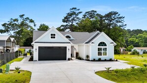 A two-story house with a garage, a covered driveway, and a well-maintained lawn. - Riviera Suites Near Beach & Boardwalk (Myrtle Beach)