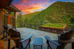 Eine Terrasse mit Sitzgelegenheit und Blick auf eine Hügelkette.
