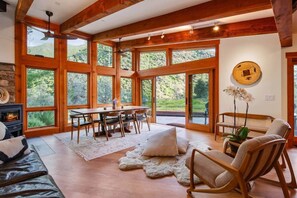 A spacious room with large windows, a fireplace, a dining table, and a cozy seating area. - The Moonstone -Yosemite Valley | Mountain View & Soaking Tub (Mariposa County)