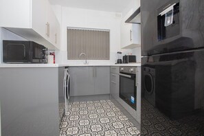 A compact kitchen with a microwave, oven, and washing machine. - Anfield City Stay | Shops & Transport | Parking (Merseyside)