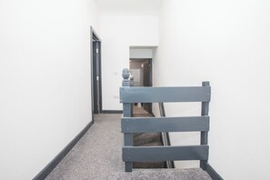 Un couloir étroit avec une chaise en bois et une porte donnant sur une autre pièce.