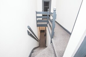 A narrow stairway with a handrail on one side and a door at the top. - Anfield City Stay | Shops & Transport | Parking (Merseyside)