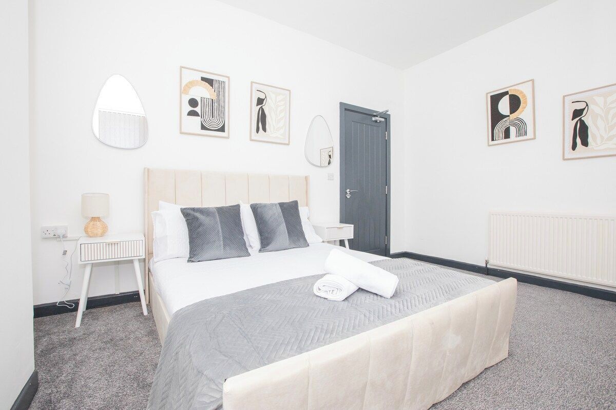 Een hotelkamer met een bed, nachtkastjes, een lamp en kunst aan de muren.