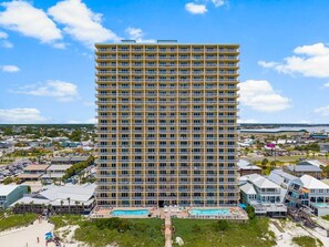 A high-rise hotel with multiple balconies, a pool area, and a view of the surrounding area. - Seychelles Beachfront Condo | Gulf Views + Pools (Panama City Beach)