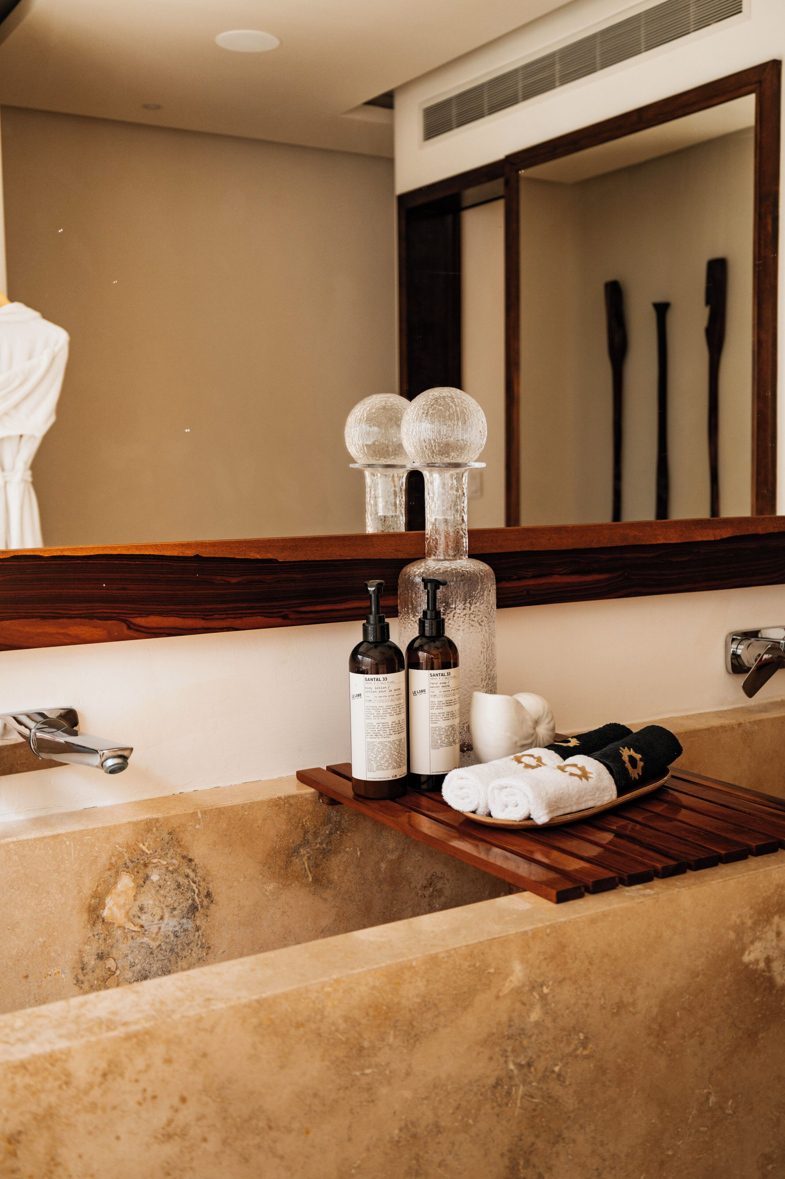 A bathroom with a bathtub, a wooden shelf with toiletries, and a mirror above the sink.