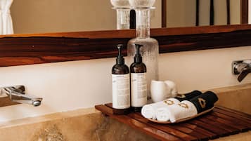 A bathroom with a bathtub, a wooden shelf with toiletries, and a mirror above the sink.
