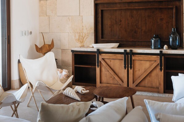 A cozy living area with a stone wall, wooden furniture, and a large TV.