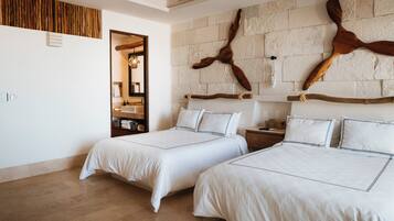 Quarto de hotel com duas camas, parede de pedra e decoração em madeira.