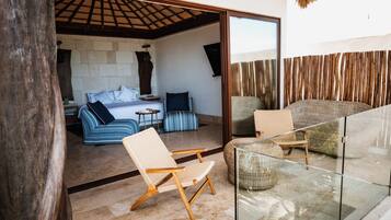 Un intérieur moderne avec un canapé, des fauteuils, une rambarde en verre et un mur en pierre.