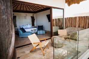 A modern interior with a sofa, chairs, a glass railing, and a stone wall.