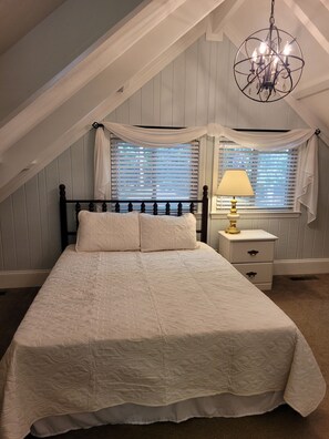Une chambre à coucher avec un lit, une table de chevet, une lampe et un lustre.
