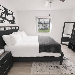 A modern bedroom with a bed, a large mirror, and a view of a building outside. - Modern & Stylish Tempe 1BR | Resort Amenities (Tempe)