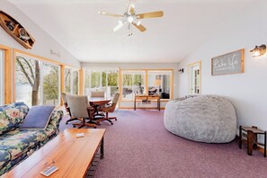 A room with a large window, a ceiling fan, a bean bag, a wooden table, and a sofa. - Tons of room!  Entertain lakeside on beautiful Pelican Lake! (Pelican Rapids)