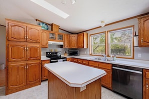 Una cocina con armarios de madera, una isla central, un microondas, una estufa y un lavavajillas.