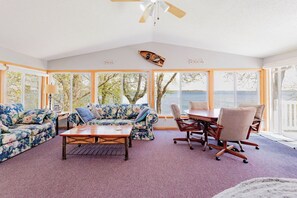 A room with a large window, a sofa, a coffee table, and a dining table with chairs. - Tons of room!  Entertain lakeside on beautiful Pelican Lake! (Pelican Rapids)