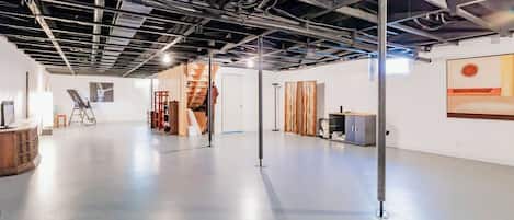 Un espacio interior con techo alto, conductos expuestos y piso de concreto pulido.