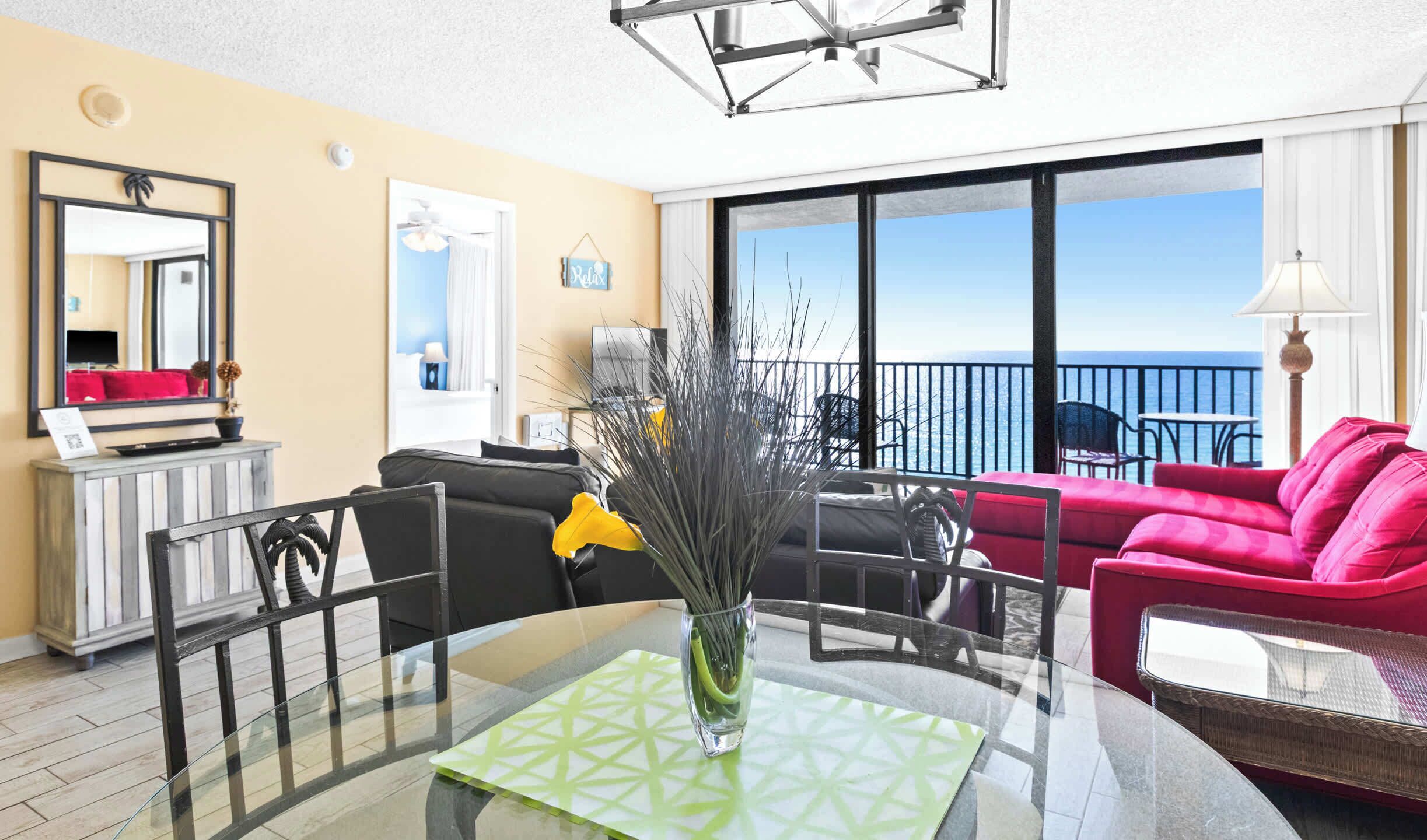 A modern hotel room with a balcony, a dining area, and a living space.