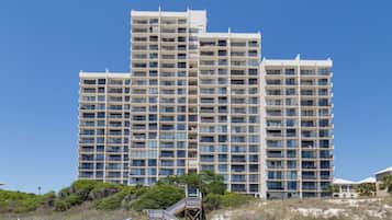 A multi-story hotel with a uniform facade, numerous balconies, and a clear sky.