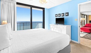 Una habitación de hotel con una cama grande, un televisor, un aparador y una silla roja.