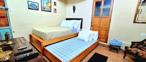 A bedroom with a bed, wooden beams, a door, and a small table with items on it.