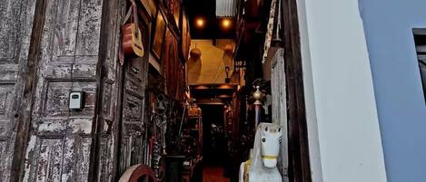A narrow alleyway with rustic wooden doors and a sign above reading 'ANTIQUE DE EL OSEO'.