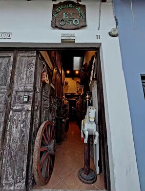 A narrow alleyway with rustic wooden doors and a sign above reading 'ANTIQUE DE EL OSEO'.