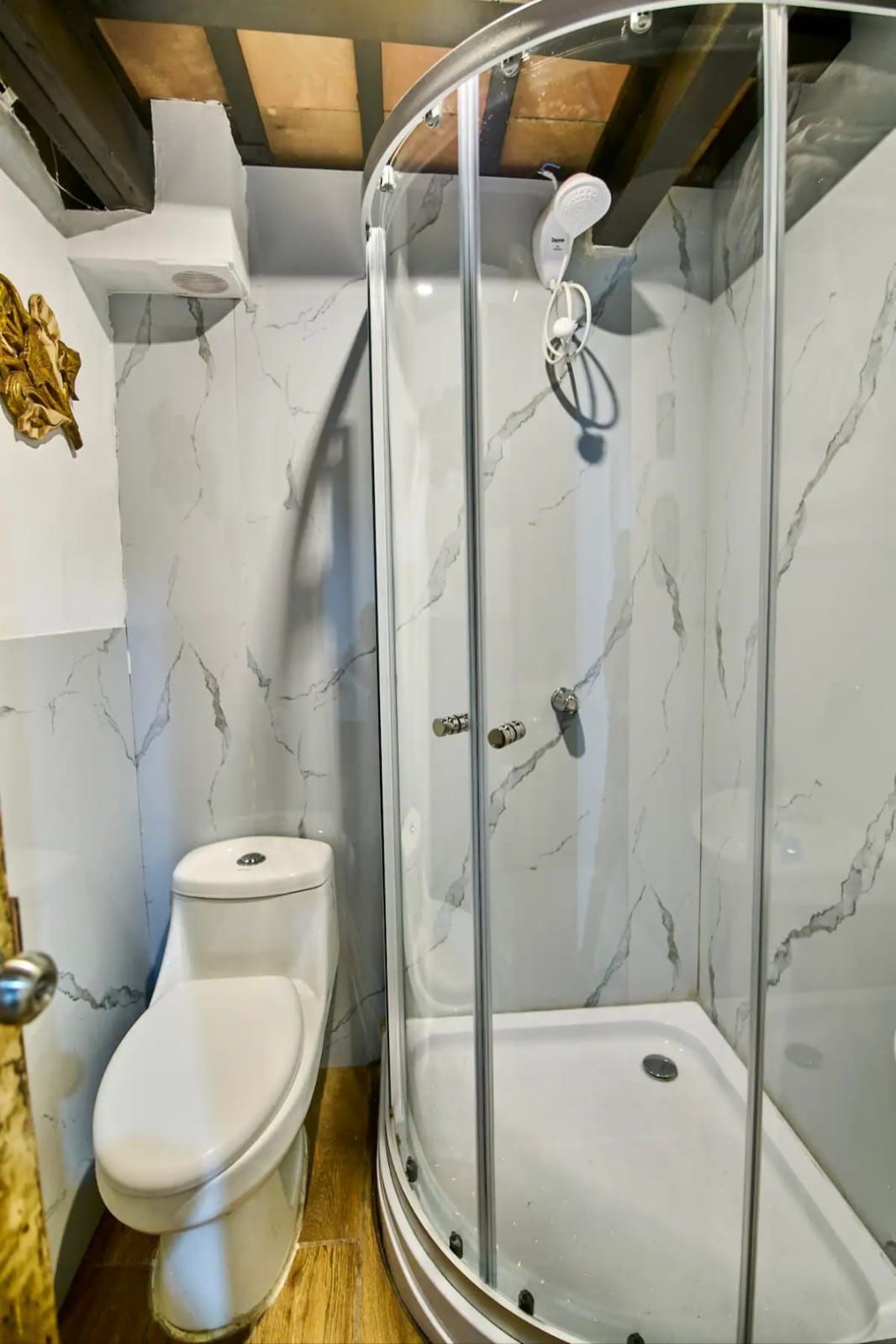 A bathroom with a glass-enclosed shower, a toilet, and marble-patterned walls.