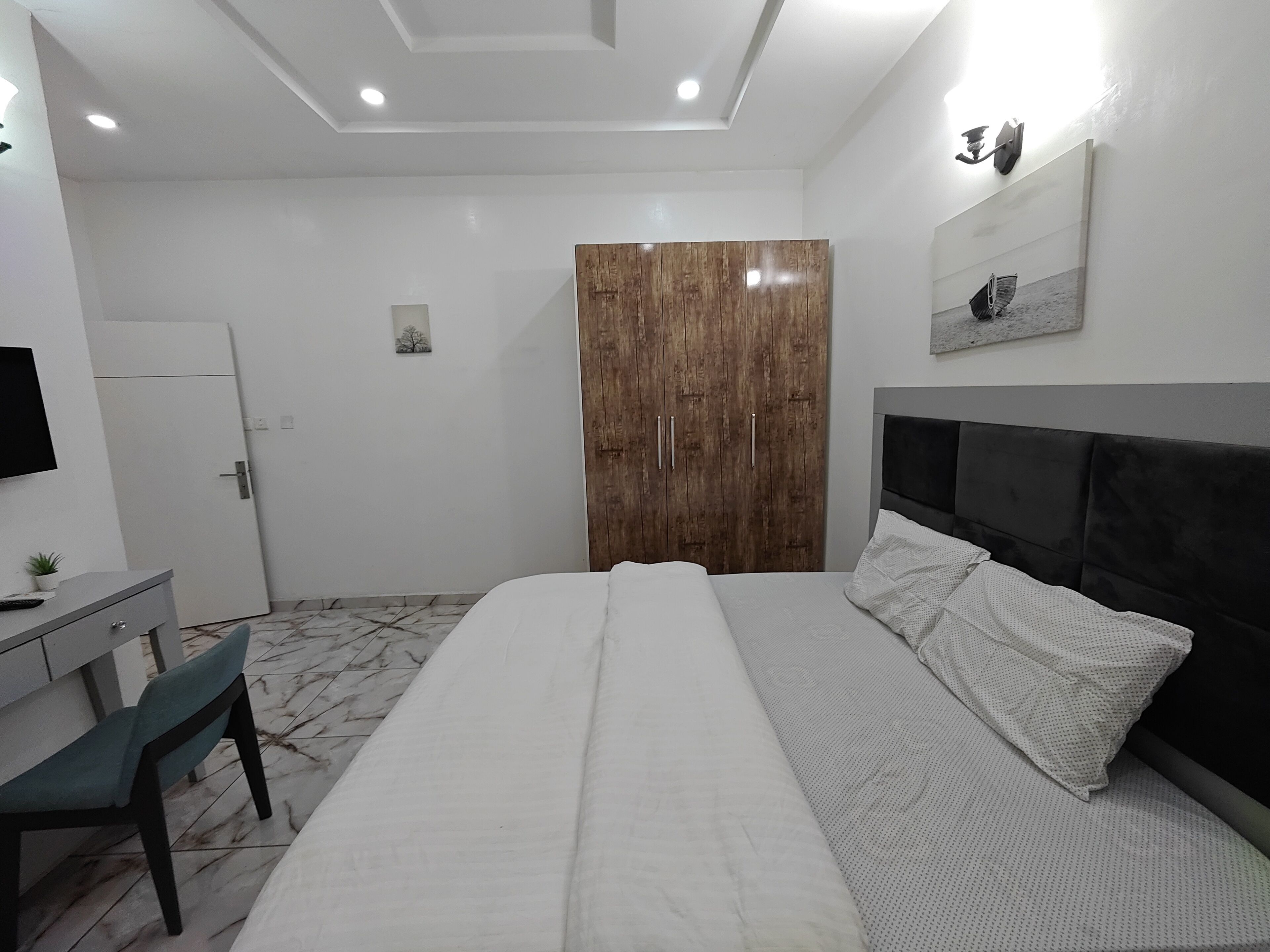 Un dormitorio con cama, escritorio, silla, armario y televisión.