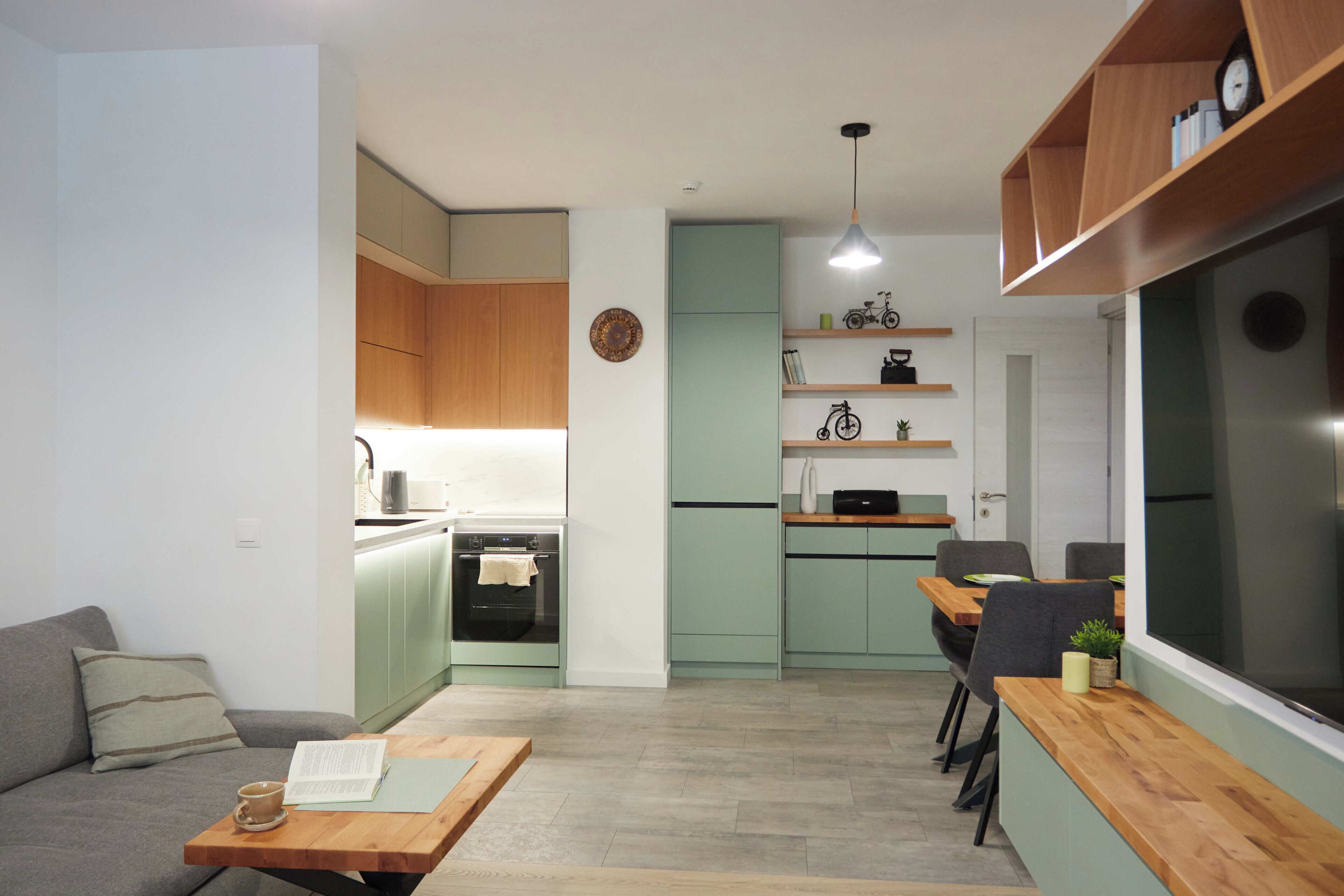 A compact living space with a kitchenette, a dining area, and a seating area with a sofa and a table.