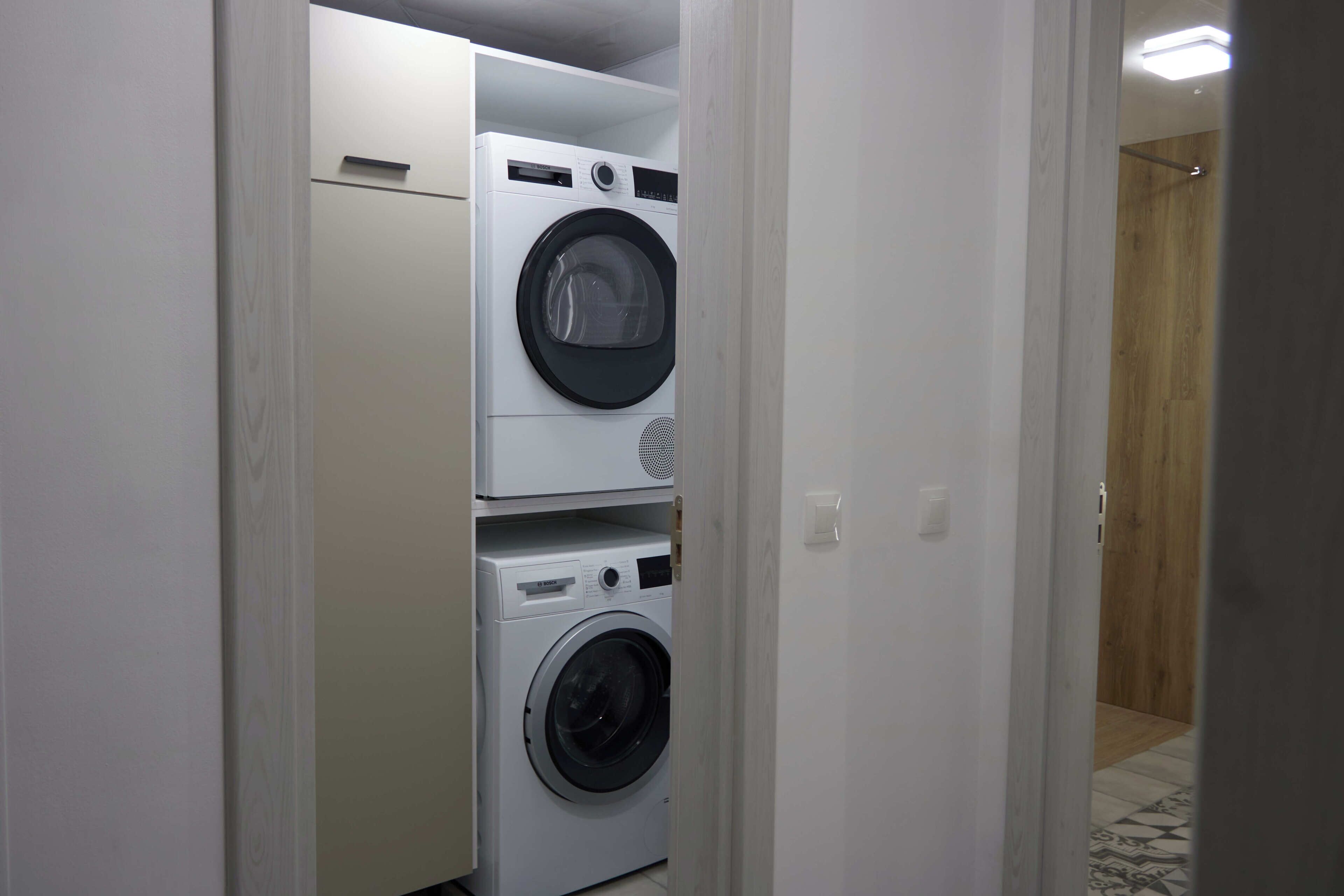 A laundry room with two stacked washing machines and a dryer.