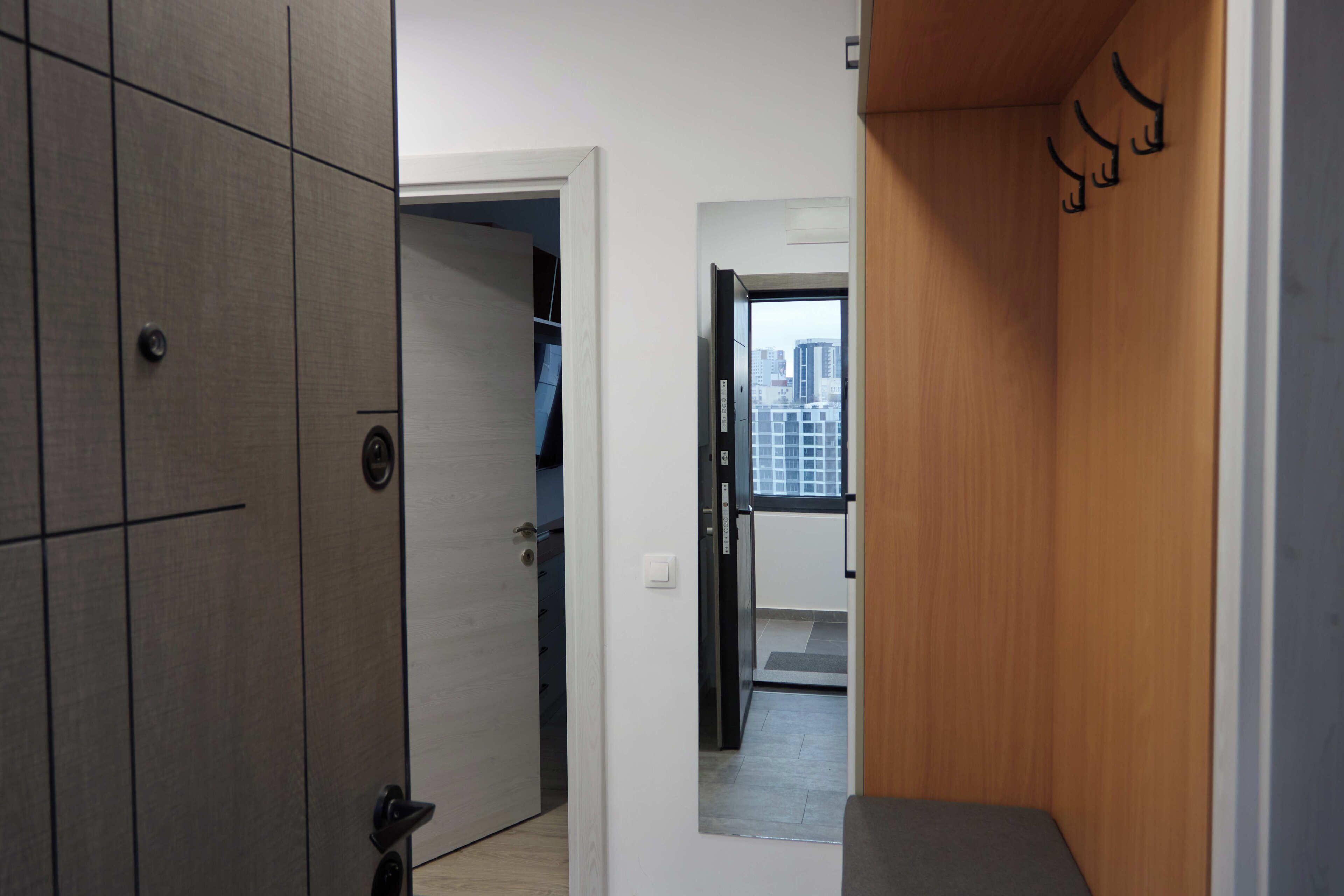 A hallway with a wardrobe, a door leading to a room with a city view, and a small seating area.